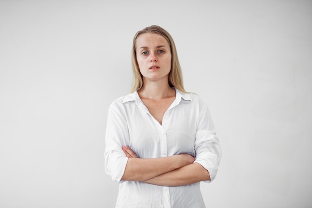 Portrait d'une fille fatiguée sans maquillage sur un mur blanc