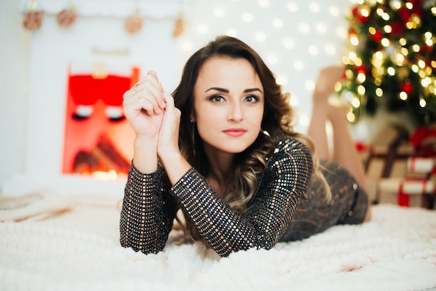 Portrait d'une fille sur le fond des décorations de Noël, des arbres de Noël de cheminée et des guirlandes