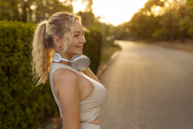 Portrait d'une fille en forme se préparant à courir dans des vêtements d'entraînement en regardant la caméra souriante et belle