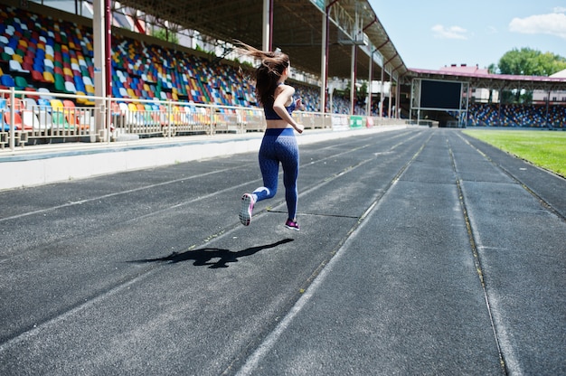 Photo portrait d'une fille forte en sportswear en cours d'exécution dans le stade.