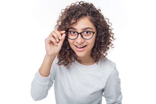 Portrait fille gaie avec des lunettes regardant intensément dans l'appareil photo sur blanc isolé.