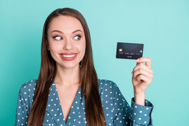 Portrait D'une Fille Gaie Positive Tenir Regarder La Carte De Crédit Porter Un Chemisier Rétro à Pois Isolé Sur Fond De Couleur Sarcelle