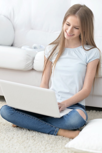Portrait d'une fille heureuse à l'aide d'un ordinateur portable