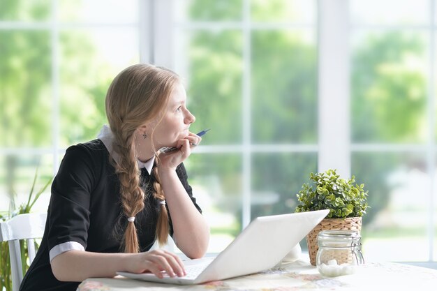 Portrait d'une fille heureuse à l'aide d'un ordinateur portable