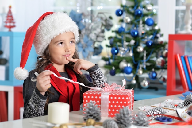 Portrait de fille heureuse en bonnet de Noel assis avec cadeau de Noël