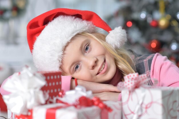 Portrait de fille heureuse en bonnet de Noel assis avec des cadeaux de Noël