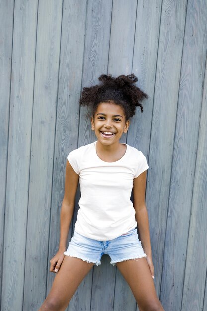 Photo portrait d'une fille heureuse debout près d'un mur en bois