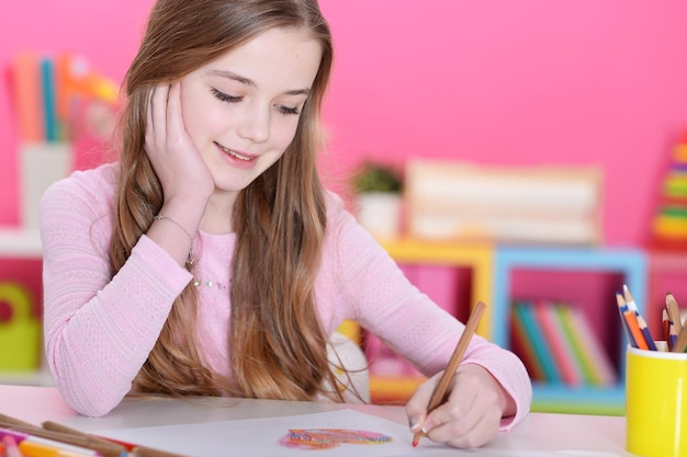 Portrait de fille heureuse dessinant avec des crayons à la maison