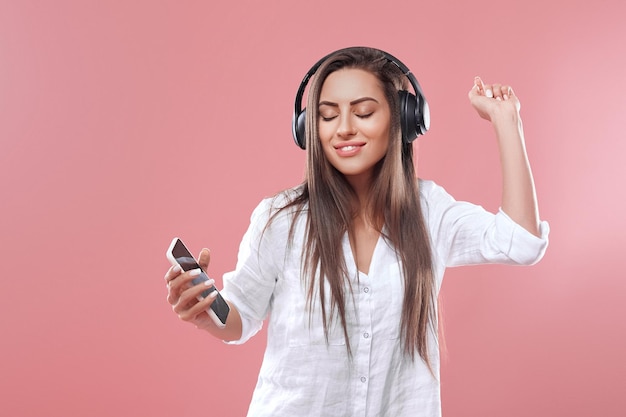 Portrait d'une fille heureuse, écouter de la musique avec des écouteurs sans fil à partir d'un smartphone