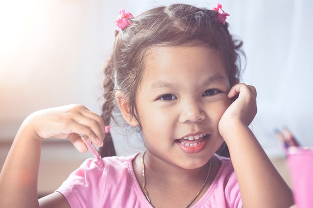 Portrait de fille heureuse enfant asiatique souriant et s&#39;amuser à dessiner et peindre dans le ton de couleur vintage