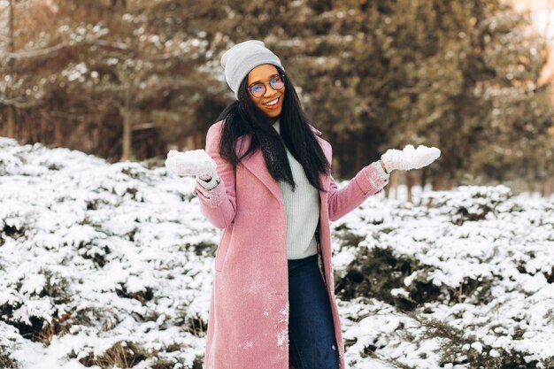 Portrait d'une fille heureuse Une jeune femme afro-américaine en lunettes et gants sourit en hiver