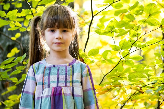 Portrait de fille heureuse jolie enfant s'amuser dans la forêt d'automne. Enfant femelle positive bénéficiant d'une journée chaude dans le parc de l'automne.