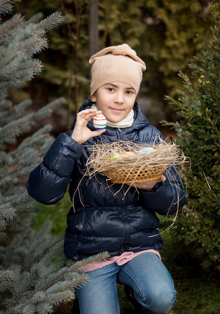 Portrait de fille heureuse montrant l'oeuf de Pâques qu'elle a trouvé sur l'arrière-cour