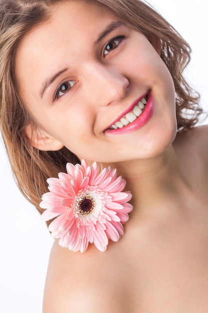 Portrait d'une fille heureuse avec une peau fraîche tenant une fleur sur un œil sur fond blanc Portrait en gros plan d'une belle femme rousse bouclée fleur pnik portant un t-shirt blanc Beauté et printemps