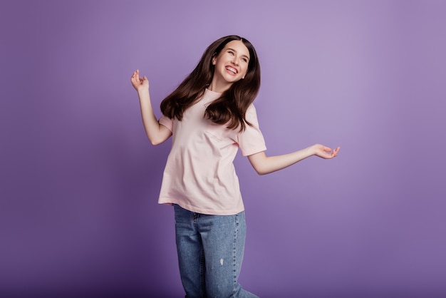 Portrait d'une fille heureuse et positive s'amuser sans soucis de bonne humeur sur le mur violet