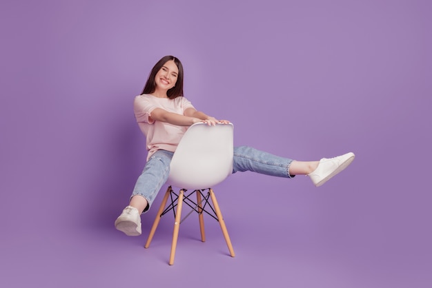 Portrait d'une fille heureuse et positive s'asseoir sur la chaise s'amuser sans soucis, lever les jambes