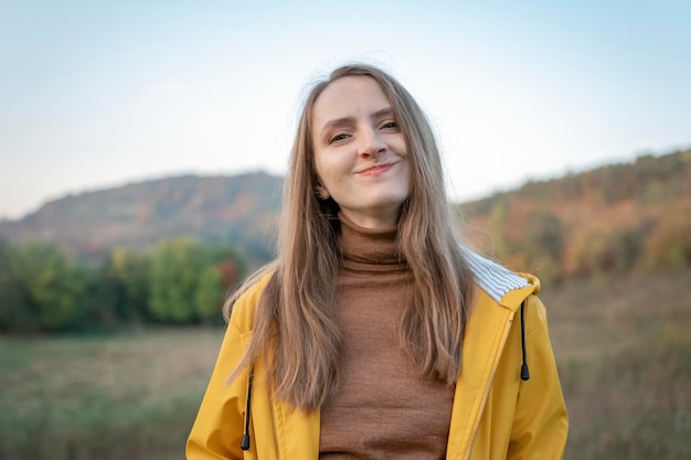 Portrait d'une fille heureuse en veste jaune sur fond montagneux Jeune femme se promène dans la nature le jour de l'automne