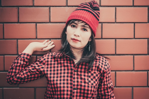 Portrait fille hipster asiatique sur fond de mur de briques elle porte un chapeau rouge style vintage concept de mode les gens de la thaïlande