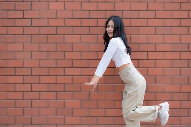 Portrait de fille hipster sur fond de mur de briqueBelle femme asiatique pose pour prendre un style photoKawaii