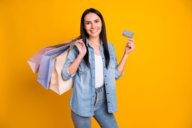 Portrait d'une fille joyeuse portant de nouvelles affaires à l'aide d'une carte de crédit