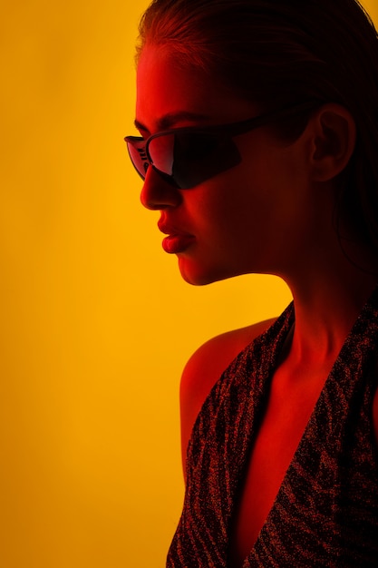 Portrait d'une fille à lunettes de soleil avec une lumière rouge