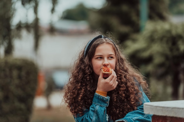 Portrait d'une fille mangeant de la pizza pendant une pause déjeuner à l'école lors de l'ouverture progressive après la fermeture de la pandémie Mise au point sélective Photo de haute qualité