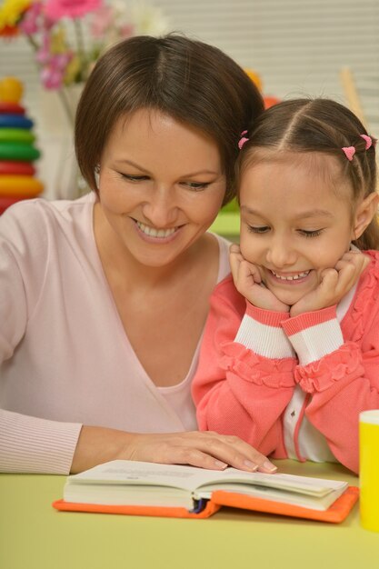 Portrait de fille et de mère lisant le livre à la maison