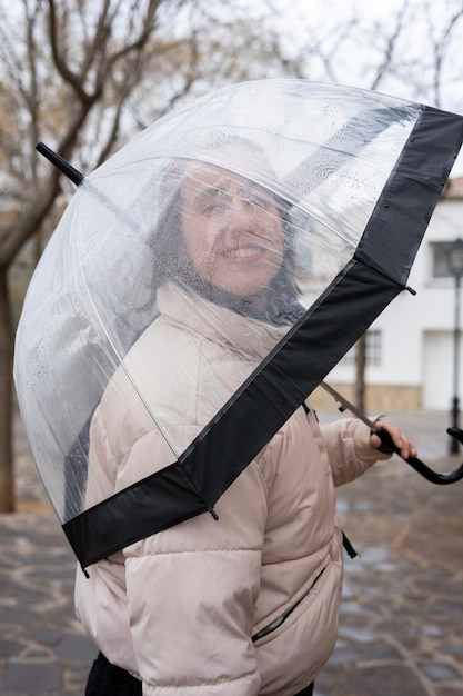 Portrait d'une fille avec un parapluie transparent sous la pluie