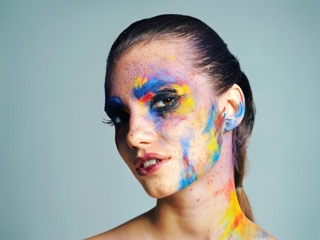 Portrait de fille et peinture faciale pour la beauté, cosmétiques et ombrages sur fond de studio. Cosmétique et créativité de la personne féminine par l'artiste avec un maquillage coloré pour l'esthétique, l'art déco et le bien-être.