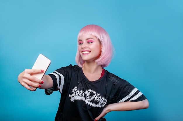 Photo portrait de fille pop portant une perruque rose et faisant selfie