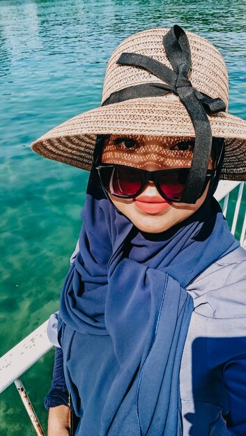 Photo portrait d'une fille portant un chapeau contre la mer