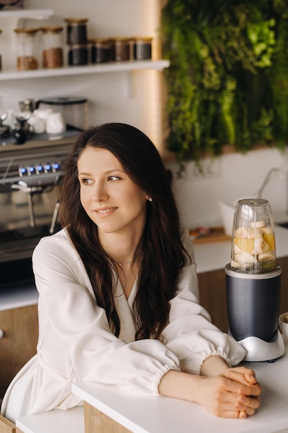 Portrait d'une fille qui fait un délicieux cocktail de fruits dans la cuisine Régime pour perdre du poids