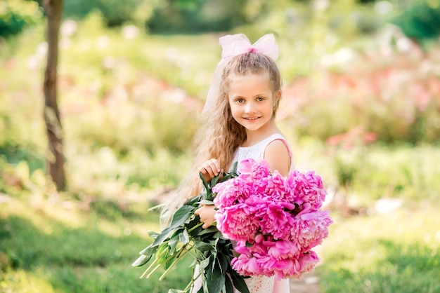 Portrait d'une fille qui rit avec un bouquet de pivoines.