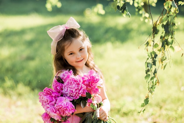 Portrait d'une fille qui rit avec un bouquet de pivoines.