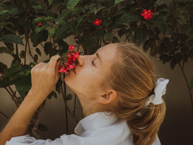 Photo portrait d'une fille qui sent les fleurs rouges