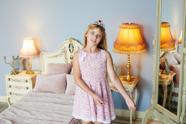 Portrait d'une fille en robe avec une couronne sur la tête à la maison