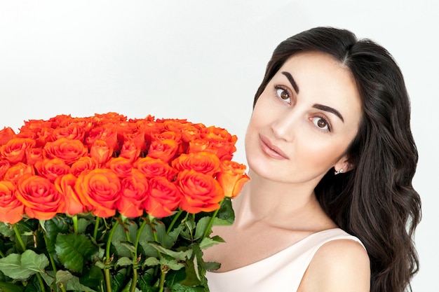 Portrait de la fille rousse qui rit avec des roses orange