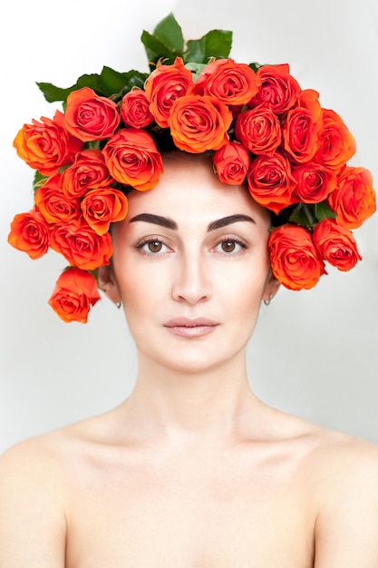 Portrait de la fille rousse qui rit avec des roses orange