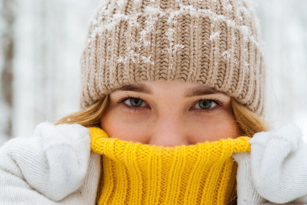 Portrait d'une fille se réchauffant avec son souffle cachant son nez dans le col d'un pull chaud