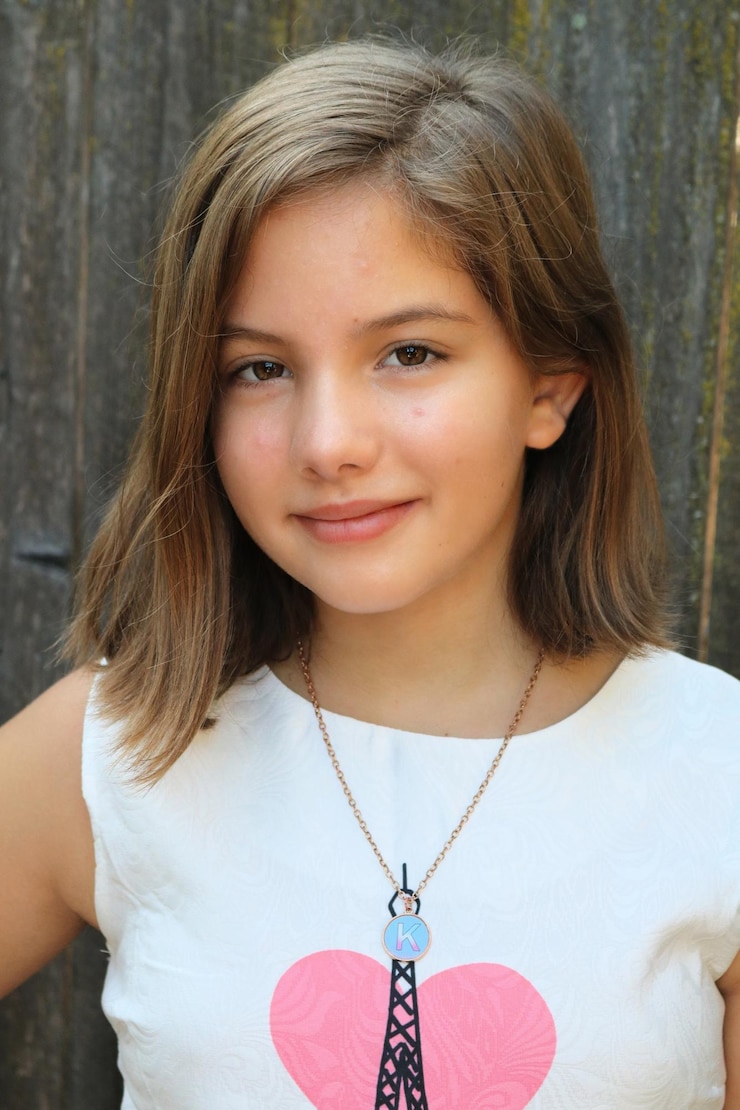 Photo portrait d'une fille souriante contre une clôture en bois