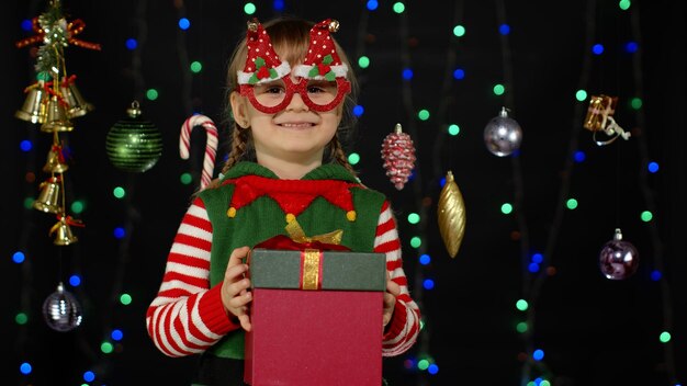 Photo portrait d'une fille souriante debout près d'un arbre de noël illuminé