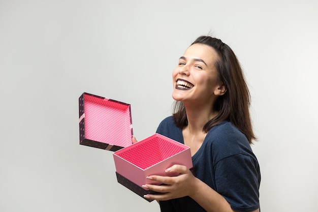 Portrait d'une fille souriante heureuse ouvrant une boîte-cadeau isolée sur fond blanc