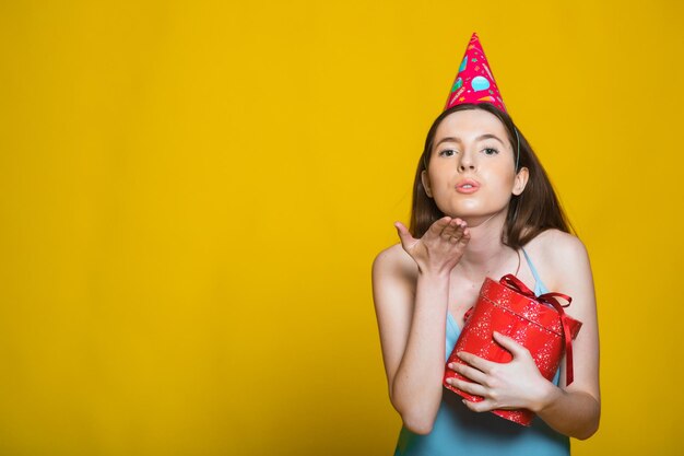 Portrait d'une fille souriante heureuse ouvrant une boîte-cadeau isolée sur fond jaune