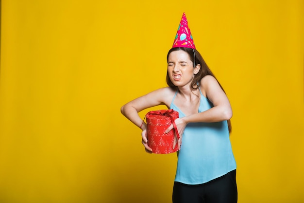 Portrait d'une fille souriante heureuse ouvrant une boîte-cadeau isolée sur fond jaune