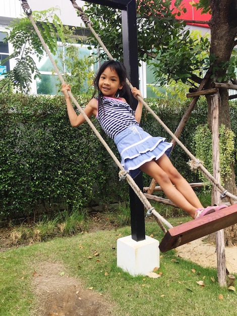 Photo portrait d'une fille souriante se balançant dans un parc