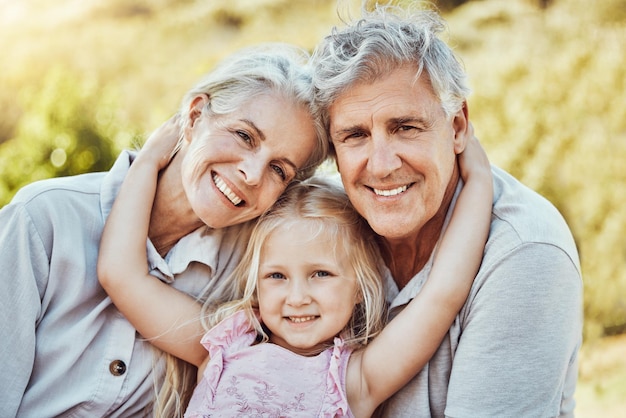 Portrait de fille et de sourire de grands-parents dans un parc extérieur familial heureux d'un pique-nique Le bonheur des enfants et les enfants avec un grand-parent âgé dans le jardin ou l'arrière-cour souriant et se liant dans la nature