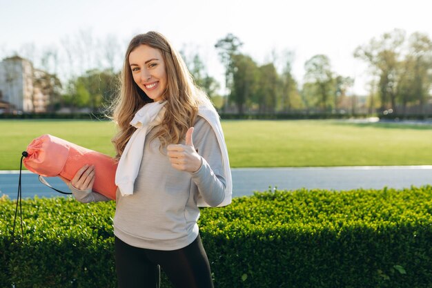 Portrait d'une fille sportive souriante au stade La fille porte des vêtements de sport Entraînement sportif Le concept d'un mode de vie sain