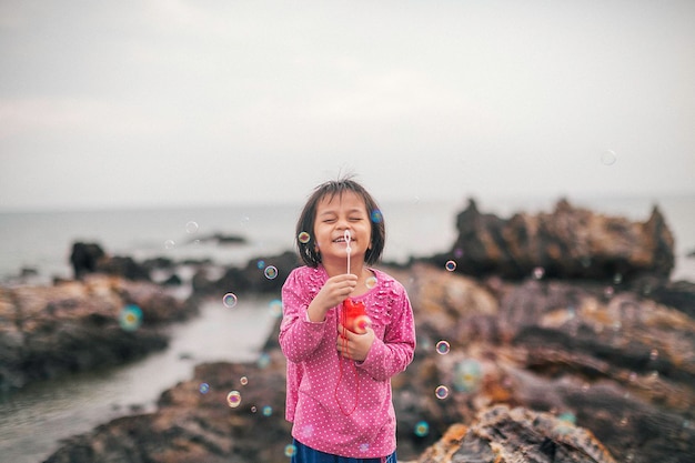 Portrait d'une fille tenant une baguette à bulles contre le ciel