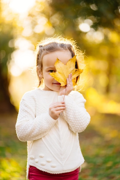 Portrait d'une fille tenant une feuille sur le visage alors qu'elle se tient sur la terre