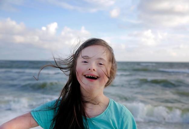 Portrait d'une fille trisomique souriante sur fond de mer